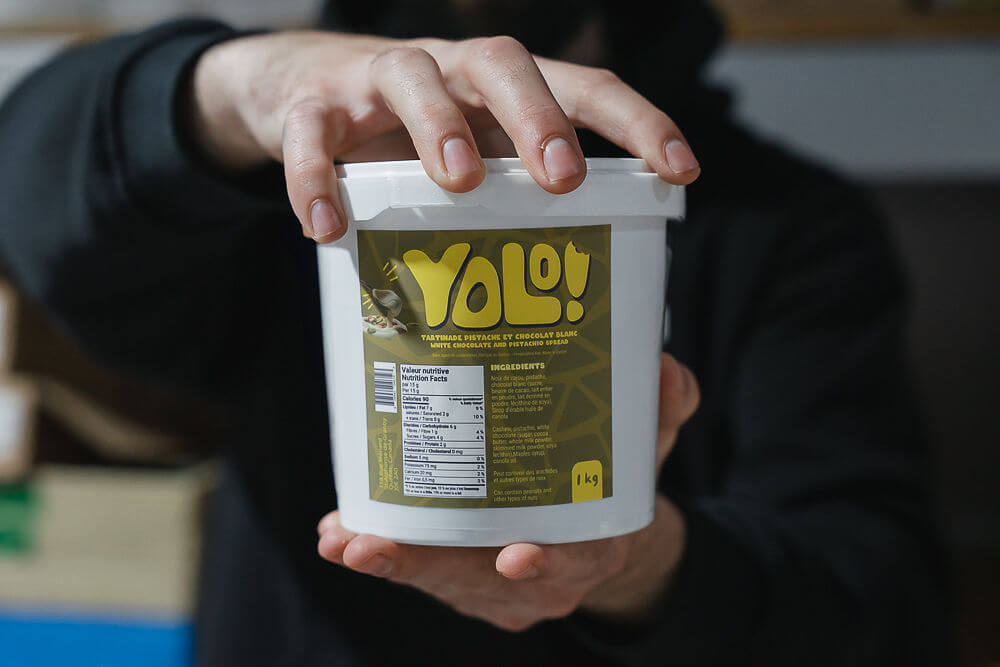 deux mains d'homme qui tienne un pot de crème de pistache Yolonuts de 1kg