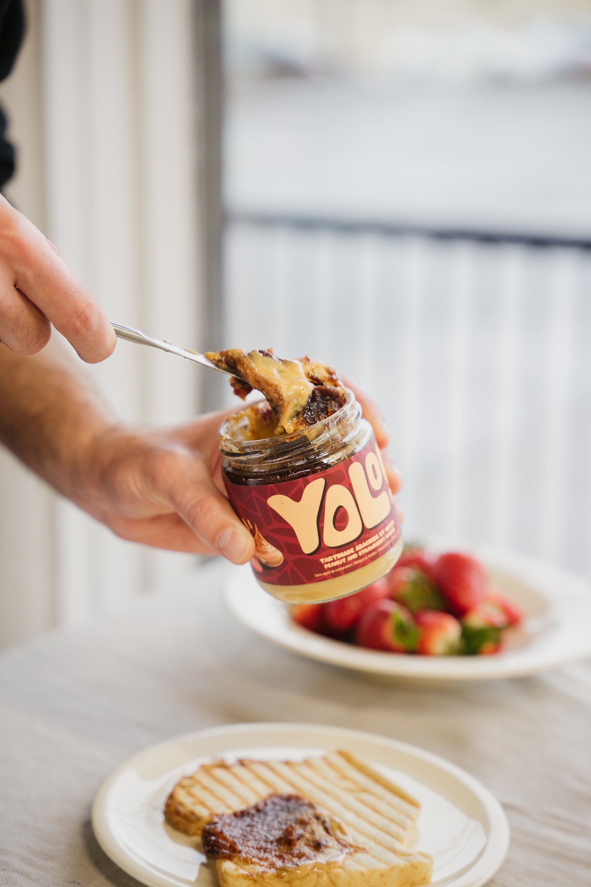 Un homme qui tartine ses roties avec une Tartinade arachide confiture de yolonuts