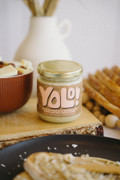 pot de Tartinade de noisette chocolat blanc  avec en arrière pan du chocolat blanc et noisettes dans un bol et des roties et des tranches de pain