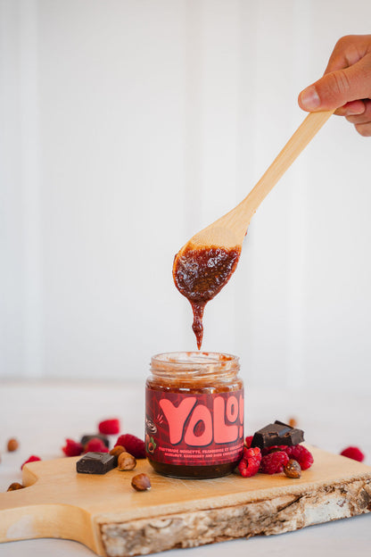 pot de Tartinade anoisette chocolat et framboise avec une cuillère au dessus du pot ouvert récoltant le contenu du pot