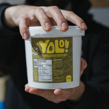 deux mains d'homme qui tienne un pot de crème de pistache Yolonuts de 1kg